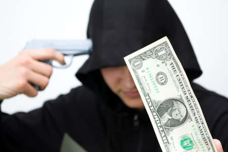 A teenager with a gun at the temple against the background of one dollar, a monetary deposit.の写真素材