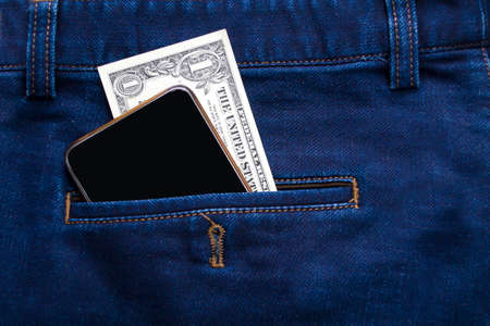 In Jeans pocket is a phone and one dollar, the concept of cheap telephony.の写真素材