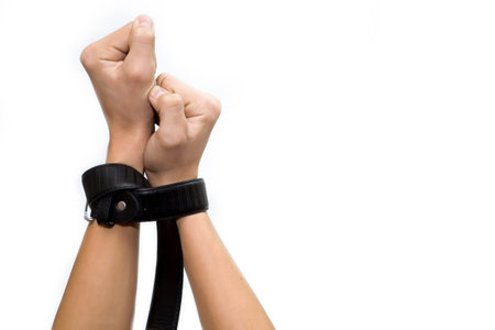 Hands clenched into fists tied with a belt on a white background, slavery to this life.