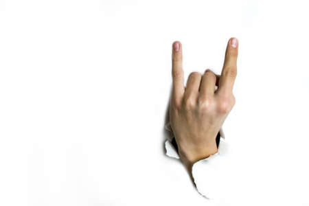 Horns of fingers made their way through a hole in the white background.の写真素材