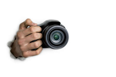 The concept of paparazzi or hidden camera, a hand holds a photo camera on a white background.の写真素材