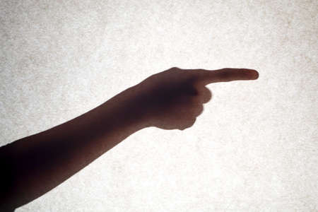 The shadow of a hand with an outstretched finger points to the side.の写真素材