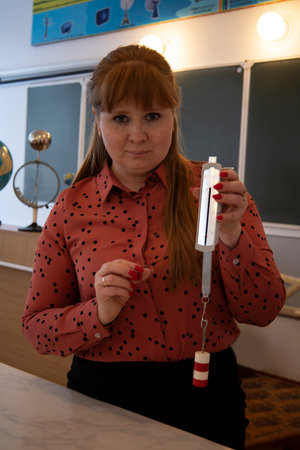 A math and physics teacher stands holding a ruler. Portrait of a teacher.