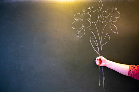 Flowers are painted on a school blackboard hand near the blackboard.の写真素材