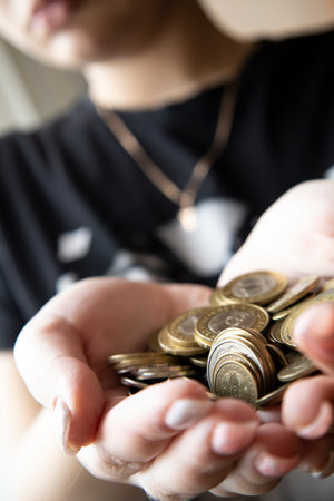 Womens hands hold a bunch of coins with a face value of 100 tenge, the subsistence minimum.の写真素材