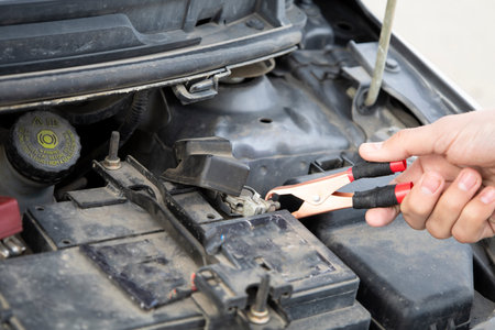Car mechanic uses battery jumper cables to charge dead battery