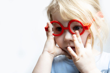 A three-year-old girl in baby glasses plays doctor.