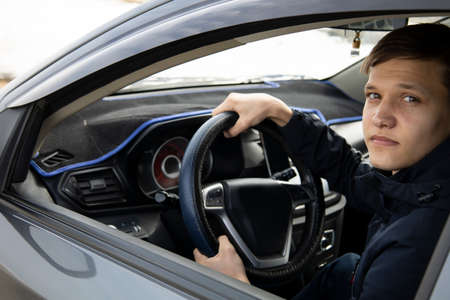 Close-up. Young handsome man looks out of a white carの写真素材