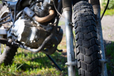 Close-up of the front wheel of the motorcycle parked on the grass.