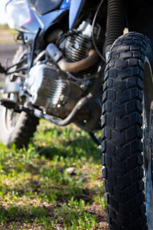 Close-up of the front wheel of the motorcycle parked on the grass.の写真素材
