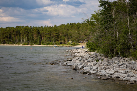 Rocky shore on a large lake in a wooded area.の写真素材