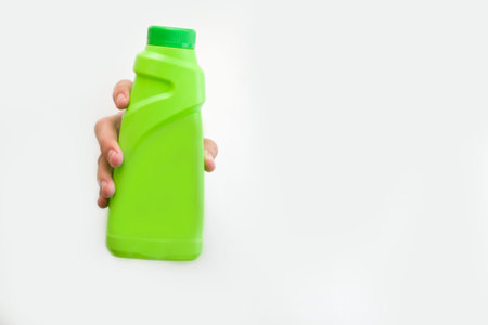 The hand holds a green bottle on a white background. High quality photo