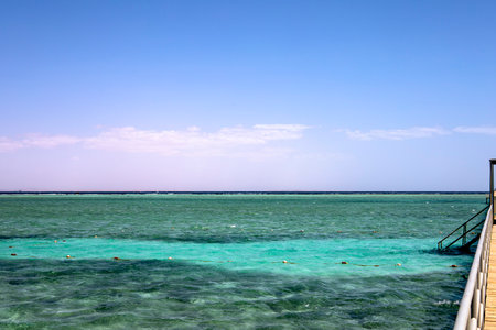 A picturesque pier overlooking the vast ocean, featuring a staircase gently leading down to the tranquil water belowの写真素材