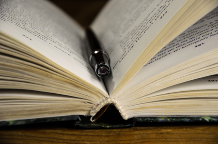 Open book and fountain pen in libraryの写真素材