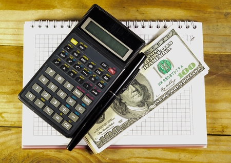 Notebook with fountain pen, banknotes and calculator on a wooden tableの写真素材