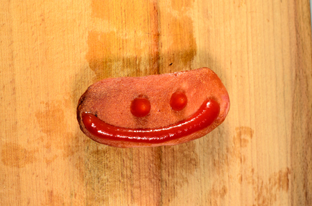 Sausage with ketchup on a wooden backgroundの写真素材