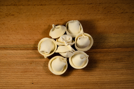 Heap of the fresh frozen dumplings on wooden tableの写真素材