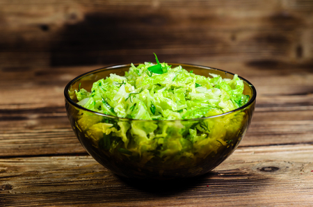 Salad with savoy cabbage and green onion in bowl on wooden tableの写真素材