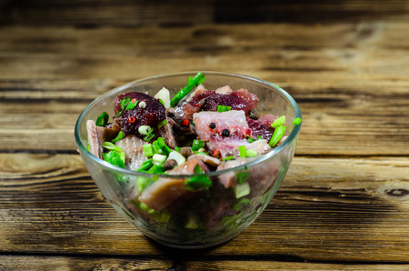 Herring with spices in glass bowl on rustic wooden tableの写真素材