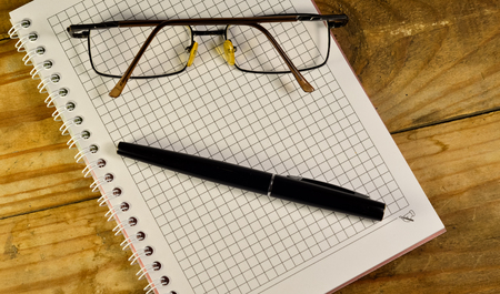 Fountain pen, glasses, and notebook on a wooden tableの写真素材