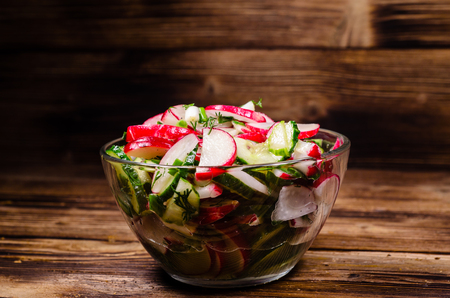 Vegetarian salad with radish and cucumbers in glass bowlの写真素材