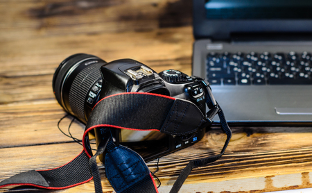 Modern DSLR camera and laptop on rustic wooden tableの写真素材