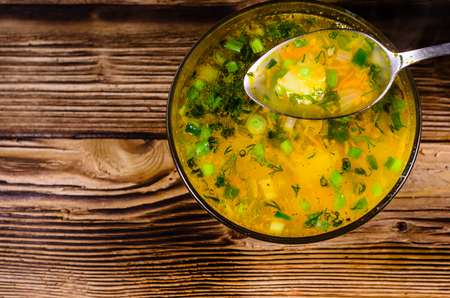 Vegetable soup in glass bowl on wooden table. Spoon with soup. Top viewの写真素材