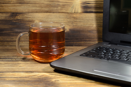 Laptop and cup of tea on rustic wooden tableの写真素材