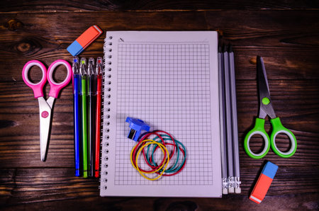 Set of different school stationeries. Notepad, scissors, pensils, on rustic wooden desk. Back to...