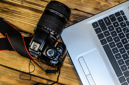 Modern DSLR camera and laptop on rustic wooden table. Top viewの写真素材