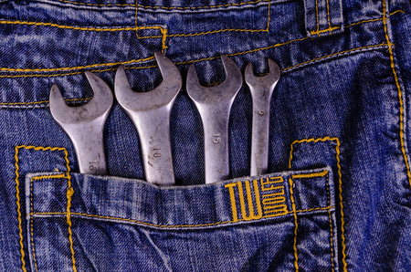 Different wrenches in a pocket of the blue jeans. Top viewのeditorial素材
