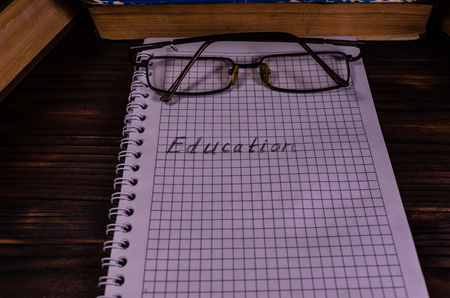 Notepad and eyeglasses in front of many books. Education inscriptionの写真素材