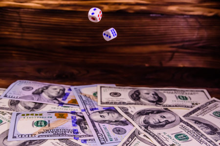Dice in flight above the one hundred dollar bills. Gamble concept
