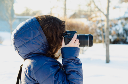 Young woman taking a photo outdoor on winterの写真素材