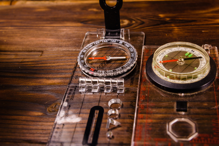 Two touristic magnetic compasses on a rustic wooden tableの写真素材