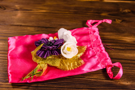 Beautiful multicolored brooch and pink bag on rustic wooden tableの写真素材