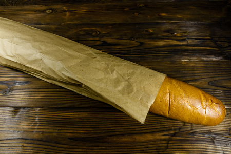 French white baguette in paper bag on rustic wooden table. Top viewの写真素材