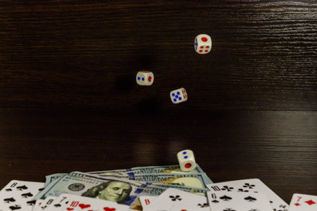 Dice in flight above the one hundred dollar bills and playing cards. Gamble concept