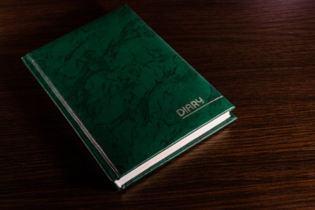 Closed green diary on dark wooden tableの写真素材