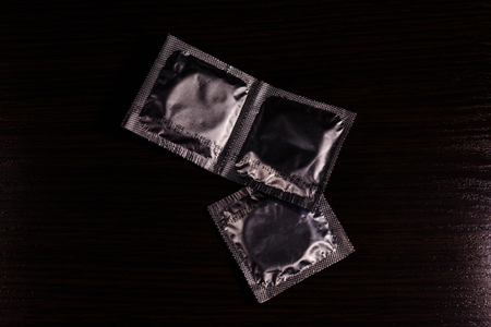 Several condoms on a dark wooden table. Top viewの写真素材
