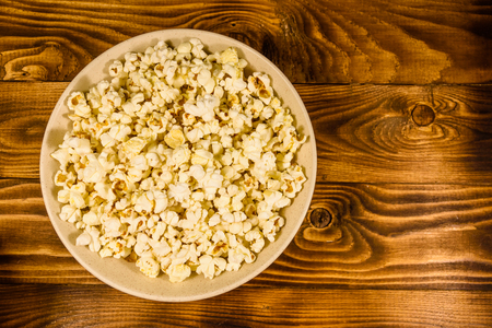 Ceramic plate with popcorn on rustic wooden table. Top viewの写真素材