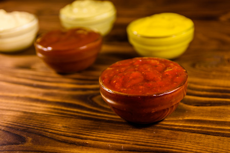 Different sauces in glass bowls on rustic wooden tableの写真素材