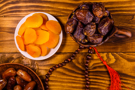 Date fruits and rosary on white wooden table. Top viewの写真素材