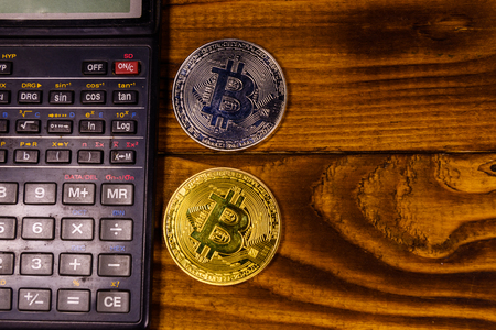 Bitcoins and scientific calculator on rustic wooden table. Top viewの写真素材
