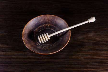 Honey spoon in ceramic dish on dark wooden tableの写真素材