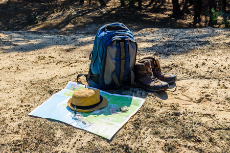 Backpack, touristic boots, map, compass and hat on groundの写真素材
