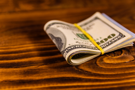 Bunch of the one hundred dollar bills with rubber on white wooden tableの写真素材