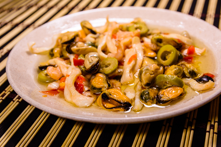 Ceramic plate with different sea food and olives on bamboo matの写真素材