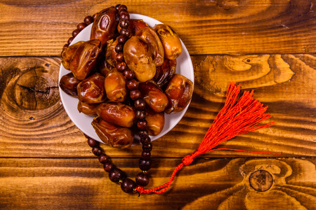 Date fruits and rosary on rustic wooden table. Top viewの写真素材