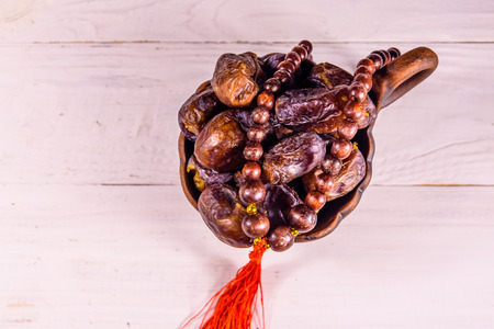 Date fruits and rosary on white wooden table. Top viewの写真素材